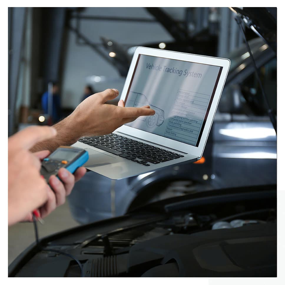 Un mecanic folosește un laptop pentru a verifica motorul unei mașini.