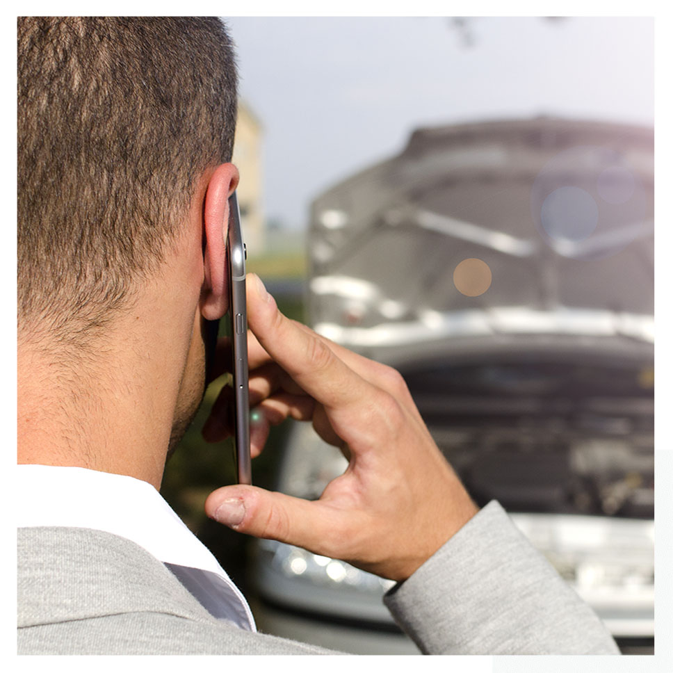 Un bărbat care vorbește la telefonul mobil în fața unei mașini accidentate, care caută asistență pentru service auto.